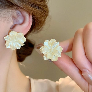 Close-up of elegant camellia stud earrings with a creamy pearlescent finish and layered petals