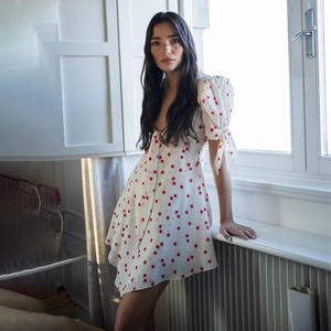Détail d'une mini robe blanche à imprimé cerise, manches bouffantes et col en V