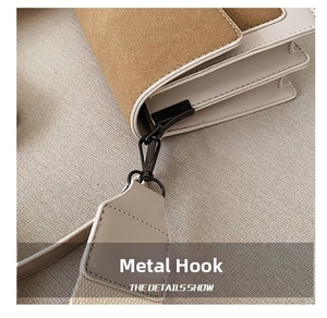 Detail of matte black metal hook and reinforced stitching on brown suede shoulder bag