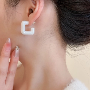 Close-up of white acrylic square hoop earring worn with glossy high-shine finish