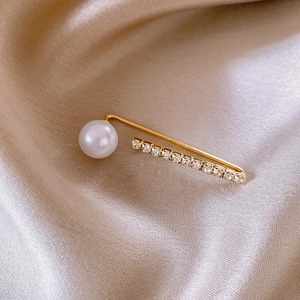 Macro detail of 14k gold plated pearl flower brooch with crystals on satin fabric