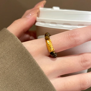 Detailed macro view of 18K gold plated cat charm and tiger eye beaded stretch ring
