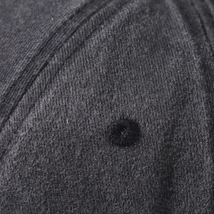 Dettaglio macro dell'occhiello ricamato sul tessuto di cotone nero del cappello da baseball