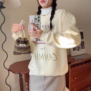 Close-up of a green striped faux fur drawstring bag shown with a white sweatshirt