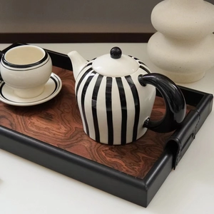 Retro black and white striped ceramic teapot and teacup set on a wooden serving tray