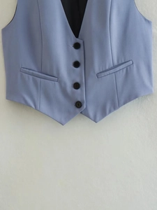 Détail du gilet bleu clair sans manches avec quatre boutons noirs et poches symétriques