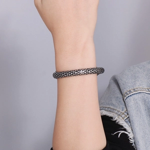 Detailed view of silver woven texture cuff bracelet on model wearing denim jacket