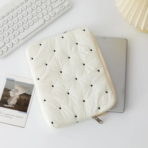 Detail of quilted beige laptop sleeve with black polka dot embroidery and zipper