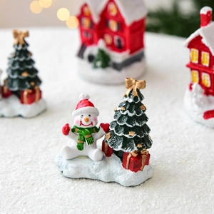 Miniature Christmas snow scene with resin snowman and tree on bokeh background