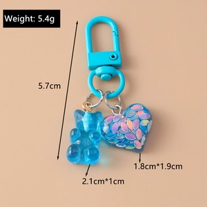Detailed view of blue bear and glitter heart keychain with 5.4g weight and size labels
