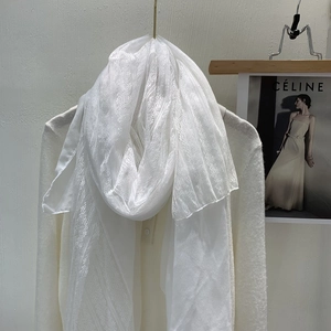 Close-up of white lightweight scarf with elegant lace trim edges on a minimalist hanger