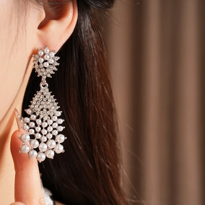 Close-up of chandelier pearl drop earrings with sparkling rhinestones on model