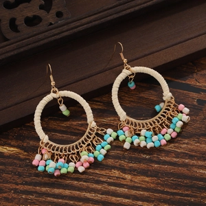 Close-up of bohemian hoop earrings with colorful seed bead tassels on dark wood background