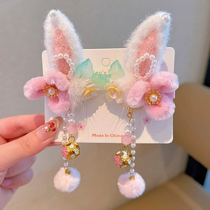 Close-up of pink plush bunny ear hair clips with pearl tassels and golden bells