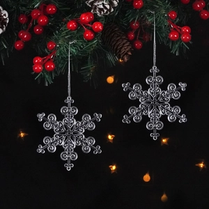 Close-up of transparent snowflake ornaments hanging on festive tree with warm bokeh lights