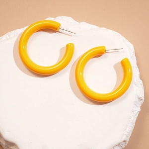 Gros plan de boucles d'oreilles C en acrylique jaune vif avec finition polie et tige argent