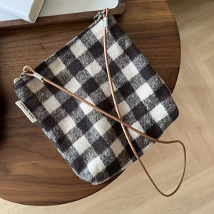 Detail of black and white gingham wool bag with zipper and brown crossbody strap