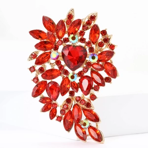 Detail view of large gold alloy brooch featuring heart-shaped red crystals and AB rhinestones