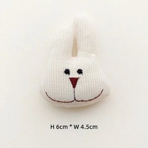 Macro detail of hand-knitted white rabbit head patch with embroidery, size 6x4.5cm