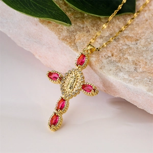 Détail du pendentif croix dorée avec pierres marquises rouges et relief de la Vierge Marie
