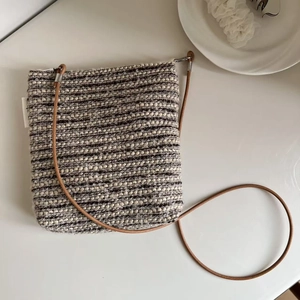 Detail of tweed crossbody phone bag with striped texture and thin brown leather strap