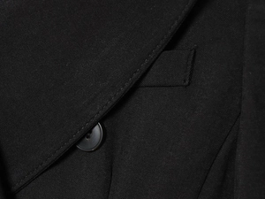 Macro shot of black twill fabric texture and button detail on a double-breasted dress coat