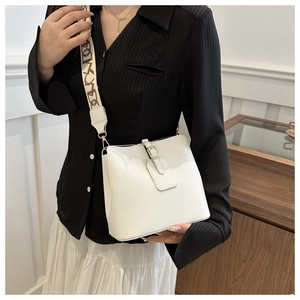 Close-up of white lychee leather bucket bag with wide black lettered webbing strap