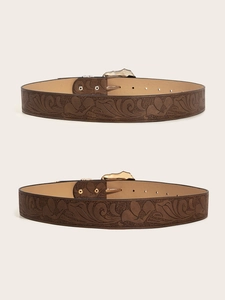 Close-up of vintage brown embossed leather belt with floral patterns and bronze buckle