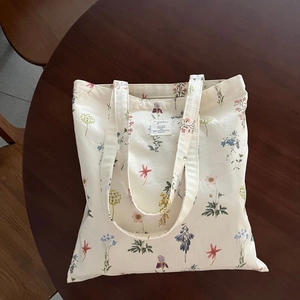 Detail view of beige cotton tote bag with colorful wildflower floral prints and fabric label