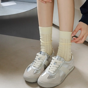 Pale yellow cotton crew socks with purple bow pattern paired with silver retro sneakers