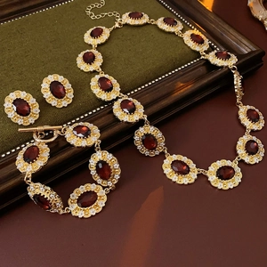 Vintage jewelry set with deep red oval gems and white flower details on dark wood