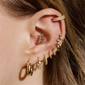 Close-up of golden S925 sterling silver ear piercings with purple gems and diamonds