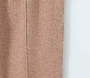 Close-up of soft camel knitted trousers showing high-quality ribbed fabric texture