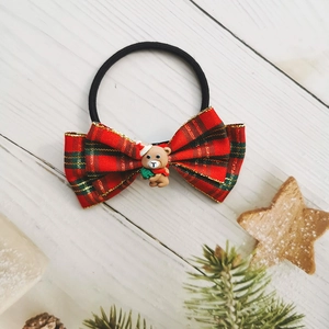 Close-up of a red plaid bow hair tie with a cute Christmas bear resin charm decoration