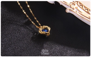 Detailed side view of golden heart pendant with deep blue crystal and white zircon border