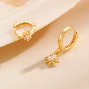 Macro shot of gold star hoop earrings with sparkling cubic zirconia on beige decor