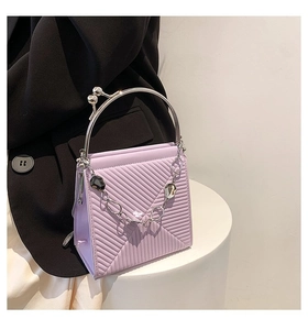 Close-up of light purple handbag featuring herringbone texture and silver ring handle