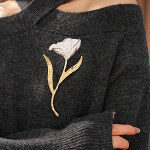 Detailed view of bicolor flower brooch on a sweater showing metallic petal textures