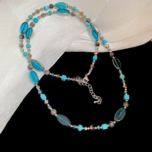 Détail du collier de perles colorées avec perles bleu ciel et turquoise sur de la soie