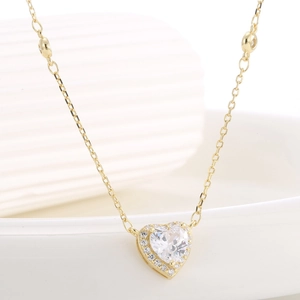 Elegant gold heart pendant necklace with clear zircon stones on a white ceramic plate