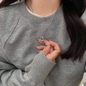 Detailed close-up of a silver irregular geometric pendant on a black wax cord necklace