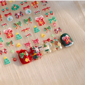 Detail of 3D embossed Christmas nail stickers featuring red bows and festive tree patterns