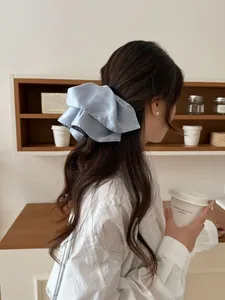 Close-up of elegant light blue satin bow hair claw clip worn on a low ponytail