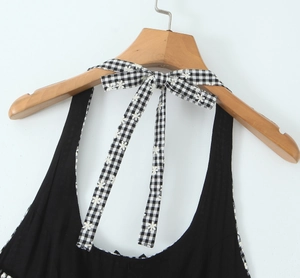 Close-up of black summer dress with a black and white checkered bow tie detail