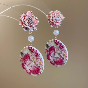 Detail of pink rose ear studs with white pearl and butterfly floral relief pendant