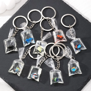 Detailed flat lay of nine creative miniature tropical fish bag resin keychains on stone