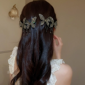 Detail of sparkling diamond butterfly hair clip with tassel chains worn by model