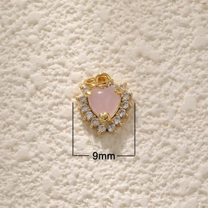 Macro detail of 18K gold plated heart pendant with pink gemstone and 9mm width scale