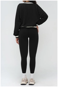 Detail of color-block ribbed cuffs and hem on a black long-sleeve athletic sweatshirt