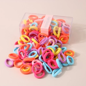 Macro view of colorful macaron elastic hair ties spilling from a transparent storage box